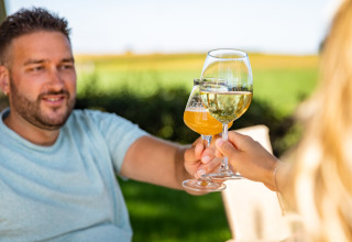 Deux personnes trinquent avec des verres de vin et de bière au Resort Mooi Bemelen, un parc de vacances à Limbourg.