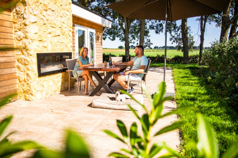 Couple profitant d'une terrasse ensoleillée au Resort Mooi Bemelen, Limburg, Pays-Bas, avec vue champêtre.
