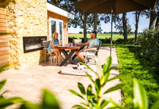 Couple profitant d'une terrasse ensoleillée au Resort Mooi Bemelen, Limburg, Pays-Bas, avec vue champêtre.