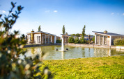 Ferieboliger ved en dam med springvand på Resort Mooi Bemelen i Limburg, Holland, under klar blå himmel.
