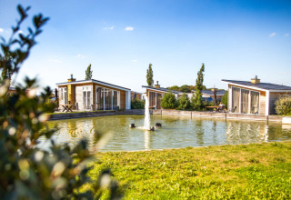 Vakantiehuisjes bij een vijver met fontein in Resort Mooi Bemelen, Limburg, Nederland, op een zonnige dag.