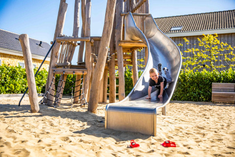 Niño jugando en un tobogán en Resort Mooi Bemelen, parque vacacional en Limburg, Países Bajos, día soleado.