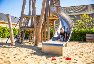 Bambino gioca sullo scivolo nel parco giochi di Resort Mooi Bemelen, villaggio vacanze in Limburgo, Olanda.