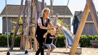 Madre empuja a su hijo en un columpio en Resort Mooi Bemelen, parque infantil en Limburg, Países Bajos.