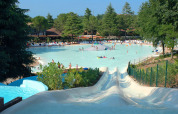 Waterpark at a lodge with swimming pool, water slides, sun loungers and trees on a bright sunny day.