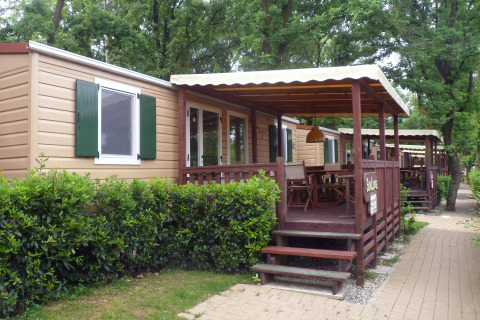 SunLodge Redwood en Altomincio Family Park, Italia, con terrazas de madera y arbustos verdes a su alrededor.