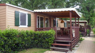SunLodge Redwood en Altomincio Family Park, Italia, con terrazas de madera y arbustos verdes a su alrededor.