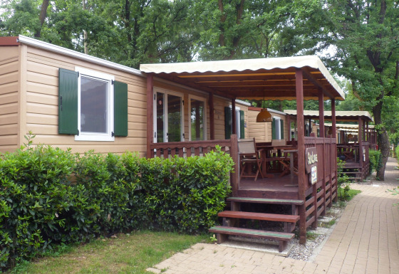 SunLodge Redwood en Altomincio Family Park, Italia, con terrazas de madera y arbustos verdes a su alrededor.