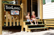 Twee kinderen zitten op de trap van SunLodge Aspen Combi bij Camping Village Cavallino in Italië.