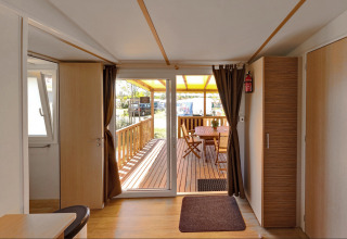 Entrada de una acogedora cabaña con terraza de madera y comedor exterior bajo techo amarillo.