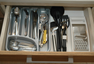 Cubiertos y utensilios de cocina organizados ordenadamente en un cajón de un alojamiento glamping.