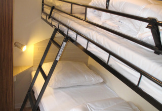 Foto de una litera moderna con edredones blancos en un alojamiento glamping iluminado por apliques.
