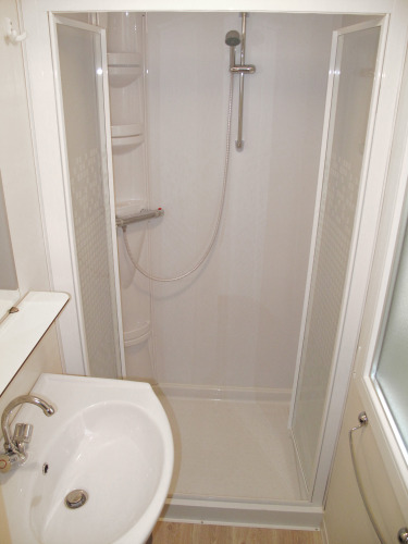 Baño compacto en un alojamiento glamping con cabina de ducha, lavabo y grifería de estilo moderno.