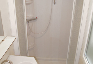 Baño compacto en un alojamiento glamping con cabina de ducha, lavabo y grifería de estilo moderno.