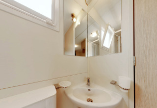 Modern bathroom with a mirror, sink, open window and toothbrush holder at SunLodge Maple in Italy.