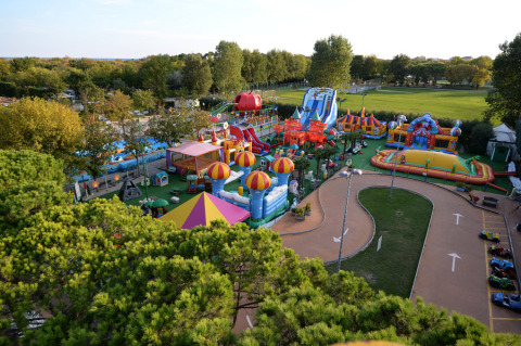 Zona de juegos y atracciones en Camping Pra'delle Torri, con áreas verdes en el parque de vacaciones de Veneto, Italia.