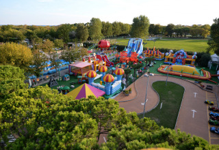 Legeplads og forlystelser i Camping Pra'delle Torri feriepark, omgivet af grønne områder i Veneto, Italien.