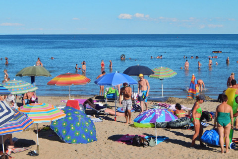 Playa concurrida con sombrillas de colores y turistas en Camping Pra'delle Torri, Veneto, Italia.
