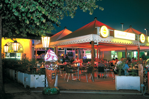 Outdoor dining area at Camping Pra'delle Torri holiday park in Veneto, Italy, illuminated at night with guests.