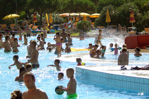 Crowds of families and children enjoy a sunny day at the pool in Camping Pra'delle Torri, Veneto, Italy.