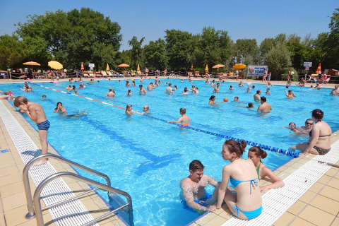 Piscina all'aperto affollata da villeggianti al Camping Pra'delle Torri, villaggio turistico in Veneto, Italia.