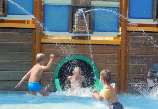 Bambini giocano e nuotano sotto schizzi d’acqua nell’area giochi nave pirata a Pra’delle Torri, Veneto.