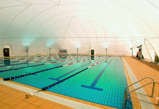 Indendørs swimmingpool med baner og moderne belysning i Camping Pra'delle Torri, Veneto, Italien.