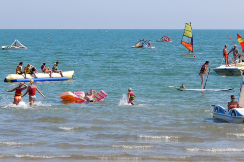 Turistas disfrutan de deportes acuáticos y actividades en la playa en Camping Pra'delle Torri, Véneto, Italia.