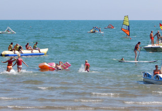 Holidaymakers enjoy water sports and beach activities at Camping Pra'delle Torri in Veneto, Italy.