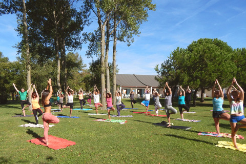 Outdoor yoga class on grass at Camping Pra'delle Torri holiday park in Veneto, Italy, sunny weather.