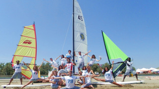 Jóvenes posando frente a coloridos veleros en la playa de Camping Pra'delle Torri, en Véneto, Italia.
