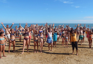 Feriecampister deltager i gruppeaktiviteter på sandstranden ved Camping Pra'delle Torri i Veneto, Italien.