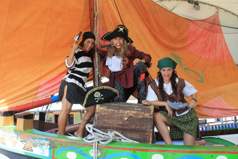 Tres personas disfrazadas de piratas posan en un barco colorido en Camping Pra'delle Torri, Véneto, Italia.