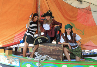Three people dressed as pirates pose on a colorful boat at Camping Pra'delle Torri, Veneto, Italy.