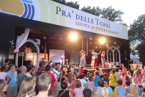 Pubblico che assiste a uno spettacolo serale dal vivo presso il Camping Pra'delle Torri a Veneto, Italia.