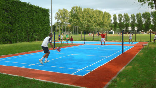 Personas juegan pádel en una pista azul en el camping Pra'delle Torri en Veneto, Italia.