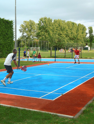 People play padel tennis on a blue court at Camping Pra'delle Torri holiday park in Veneto, Italy.