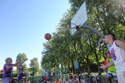 Niños y adultos juegan al baloncesto al aire libre bajo el sol en Camping Pra'delle Torri, en Véneto, Italia.