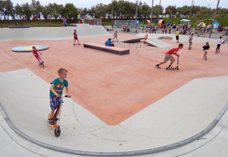 Børn leger på løbehjul og skateboards i en stor skatepark på Camping Pra'delle Torri i Veneto, Italien.