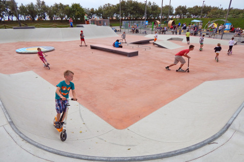 Børn leger på løbehjul og skateboards i en stor skatepark på Camping Pra'delle Torri i Veneto, Italien.