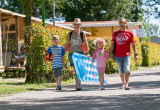 Una familia de cuatro pasea relajada por el camping Pra'delle Torri en Véneto, Italia, en un día soleado.