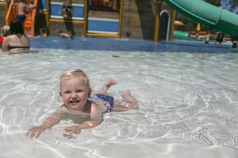 Un niño pequeño juega y nada en la piscina poco profunda del camping Pra'delle Torri en Véneto, Italia.
