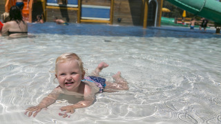 Un niño pequeño juega y nada en la piscina poco profunda del camping Pra'delle Torri en Véneto, Italia.
