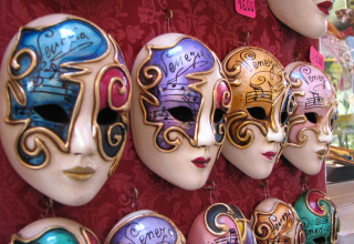 Decorative Venetian masks on display for sale, photographed near Caorle, Veneto, Italy, featuring colorful designs.