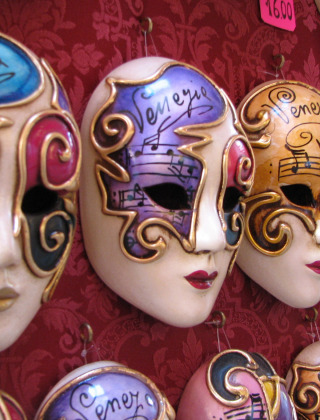 Máscaras venecianas decorativas a la venta, fotografiadas cerca de Caorle, Véneto, Italia, con diseños coloridos.