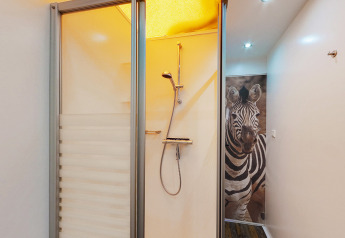 Bathroom at SunLodge Safari, Camping Pra'delle Torri, Italy, with a shower and a zebra image on the wall.