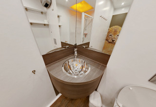 Baño moderno en SunLodge Safari, Camping Pra'delle Torri, Italia, con espejo e imagen de león en la pared.
