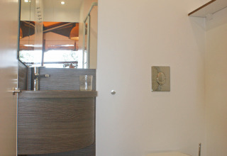Baño moderno en SunLodge Safari, Camping Pra’delle Torri, Italia, con inodoro suspendido y espejo grande.