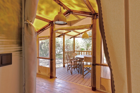Vista desde la entrada de SunLodge Safari en Camping Pra'delle Torri en Italia, con terraza y sillas.