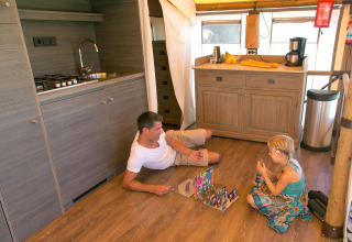Un hombre y una niña juegan a un juego de mesa en el suelo de un SunLodge Safari en Camping Pra'delle Torri.